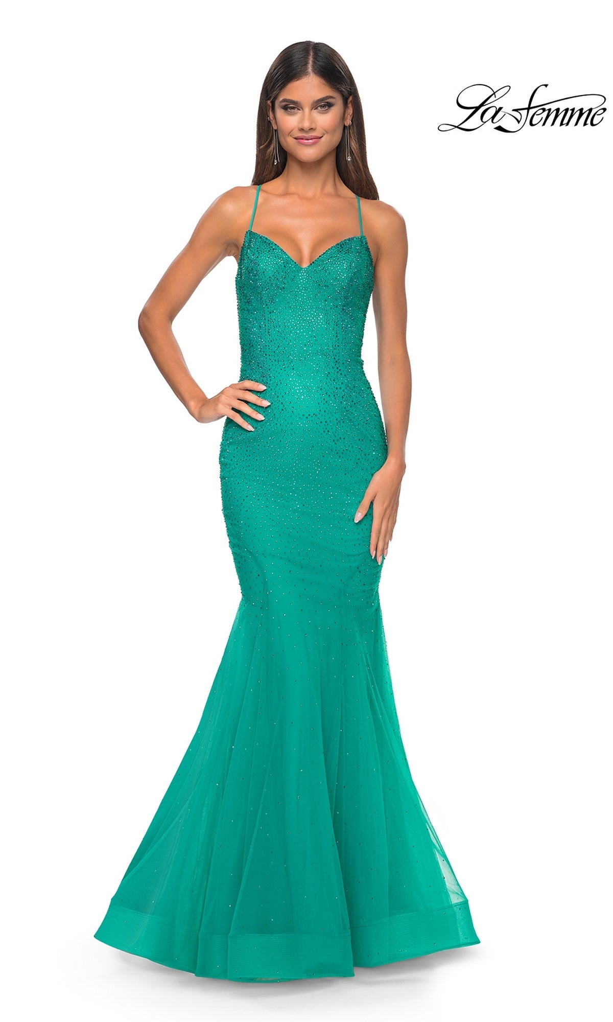 A woman wears the La Femme Embellished Long Mermaid Prom Dress 32273, a fitted sleeveless teal gown with thin straps, beaded detailing, and sparkling embellishments, standing against a plain white background.
